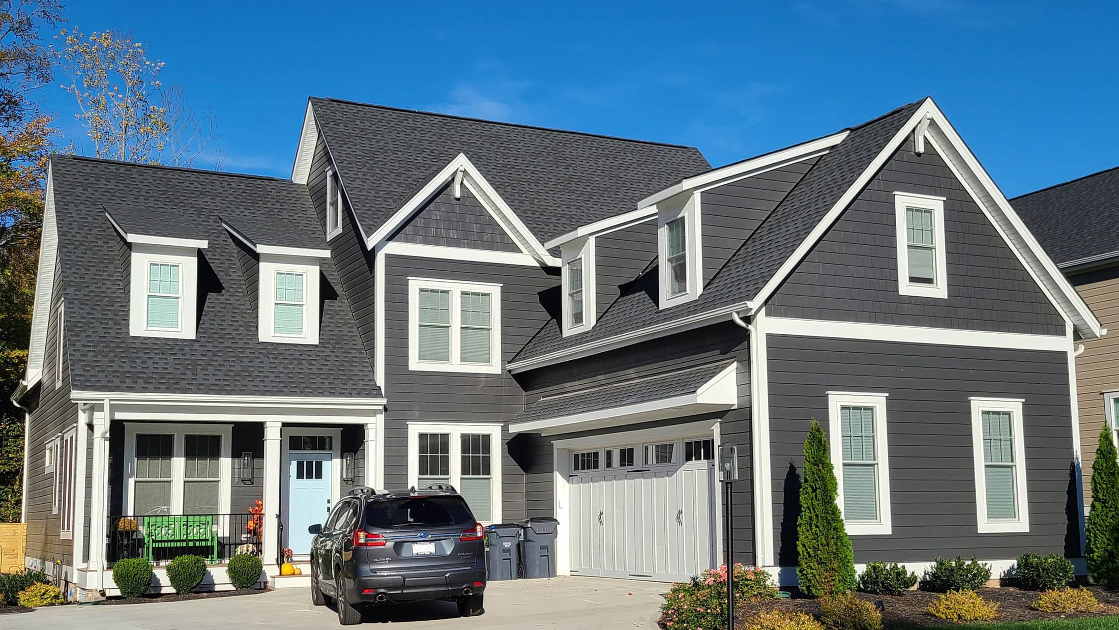 The Cedar Wood — a grey craftsman home with dormers and a two-car garage