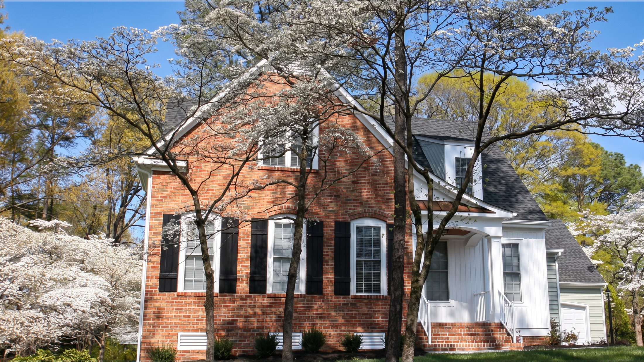 The Cotswold Manor — a brick and siding custom home in spring